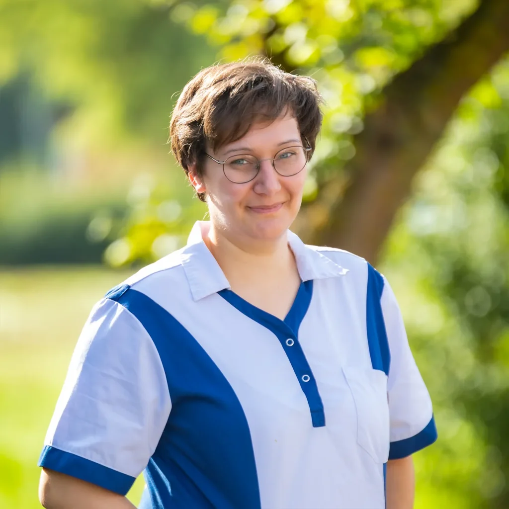 Mitarbeiterin mit runder Brille in blau-weißer Kasackbluse