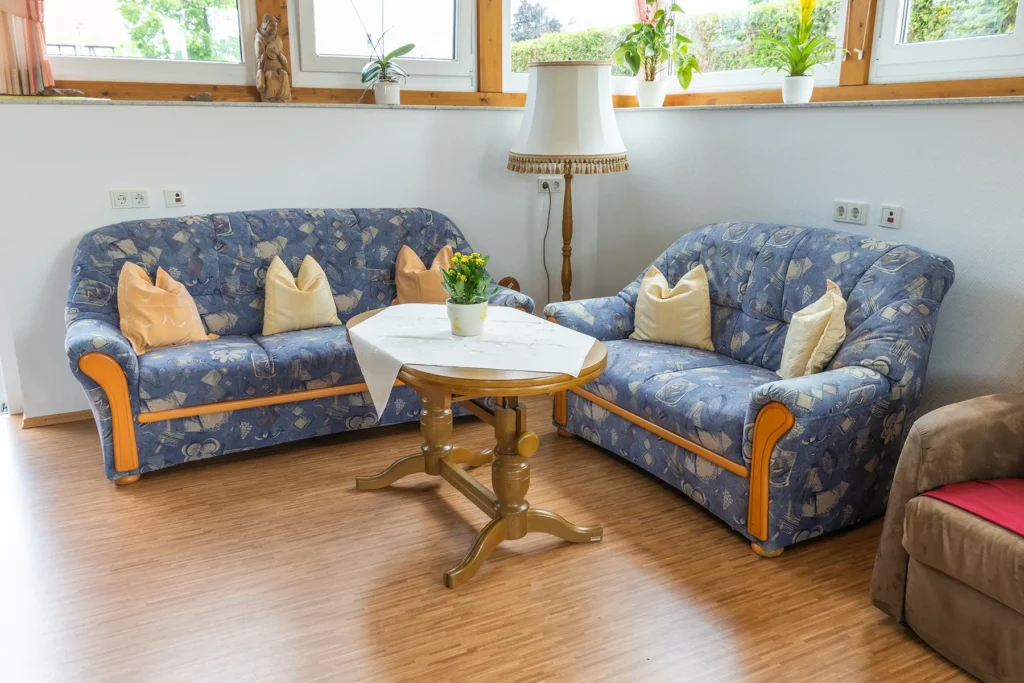 Zwei Sofas mit Kissen um einen runden Tisch vor der Fensterfront im Wintergarten